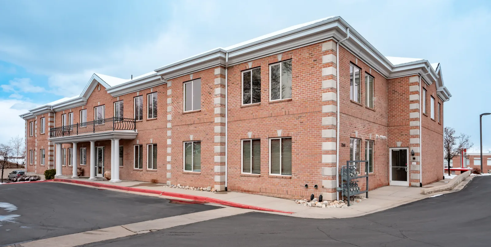 Exterior view of a two-story red brick building with columns at the entrance and white stone trim.