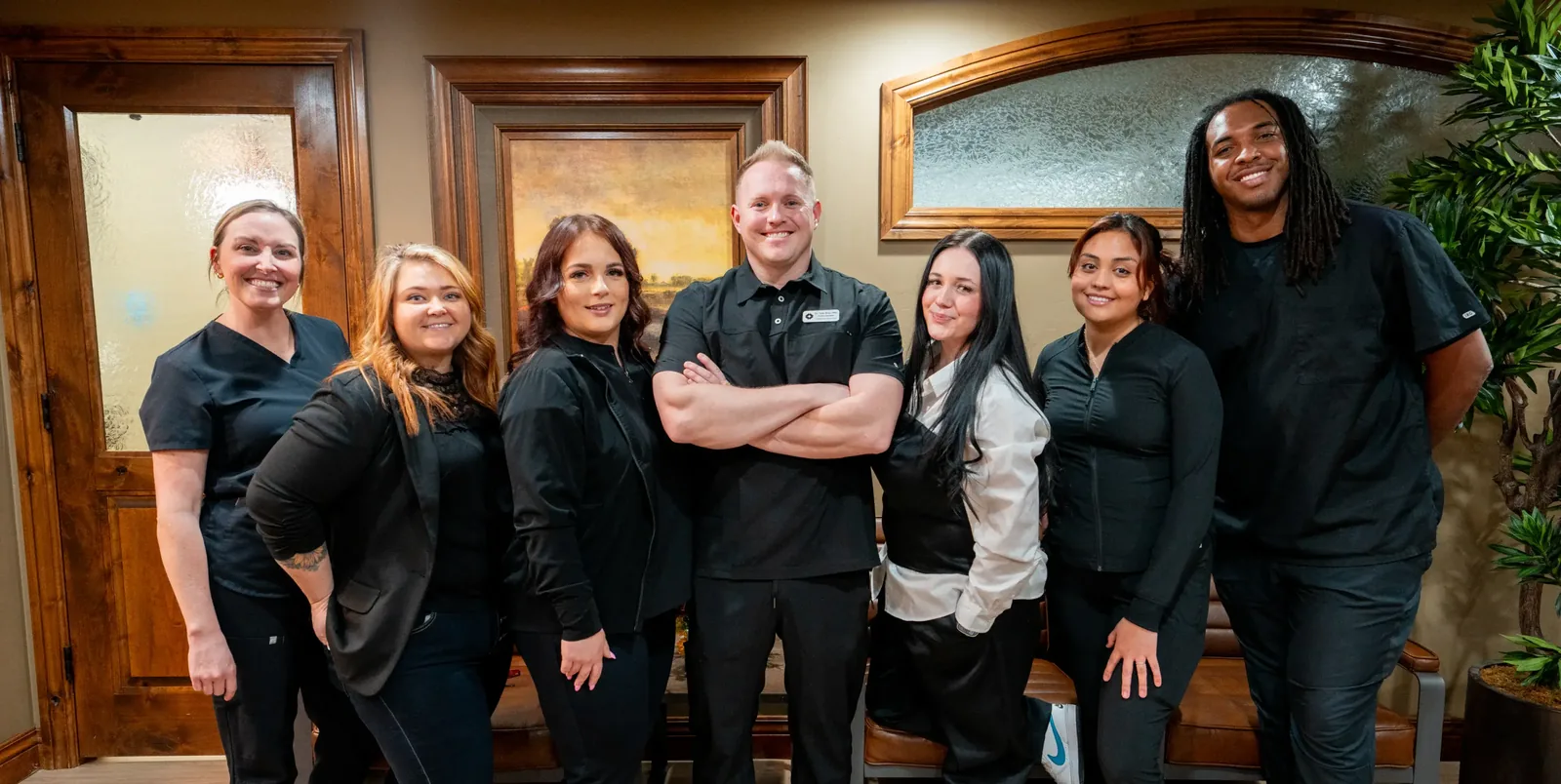 A group of dental staff members smiling and posing together inside an office.